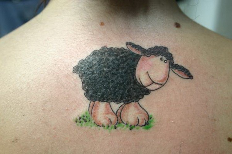 Funny black sheep on grass tattoo on back
