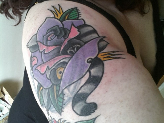 Arm Tattoo mit komischem Lemur auf violetter Rose