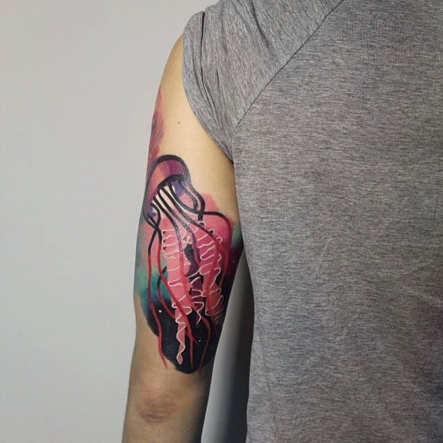 Tattoo von drölliger rosa Qualle am Oberarm
