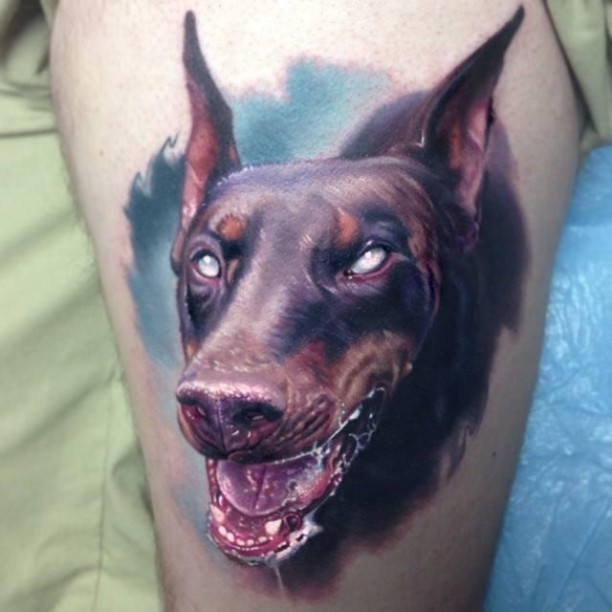 Furious doberman dog on blue background tattoo on thigh
