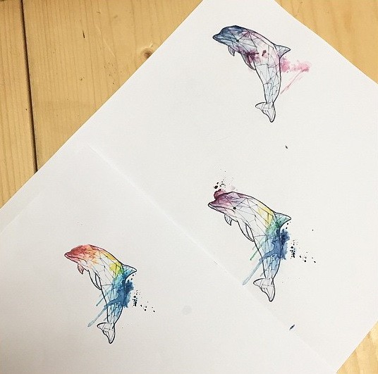 Geometric dolphin trio with rainbow watercolor effect tattoo design