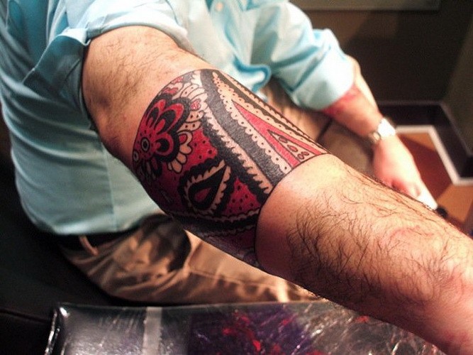 Great red-and-black tribal band tattoo on forearm