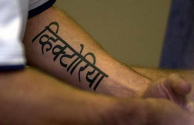 Harsh-lettered hebrew quote tattoo on arm