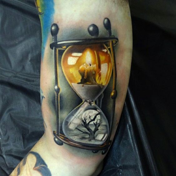 Reloj de arena con vela y tatuaje de árbol en el hombro