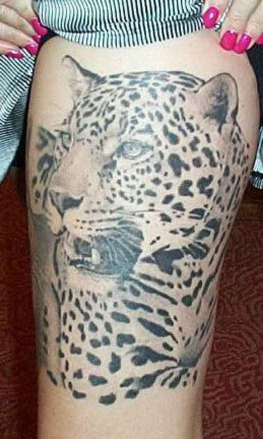 Huge black-and-white cheetah head tattoo on thigh