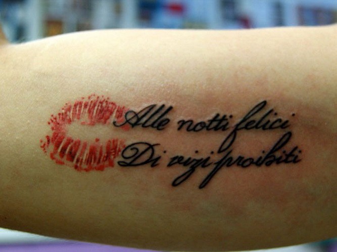 Italian quote and red kiss tattoo on arm