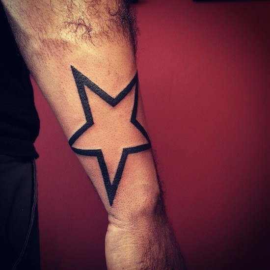 Large simple black-contour star tattoo on forearm