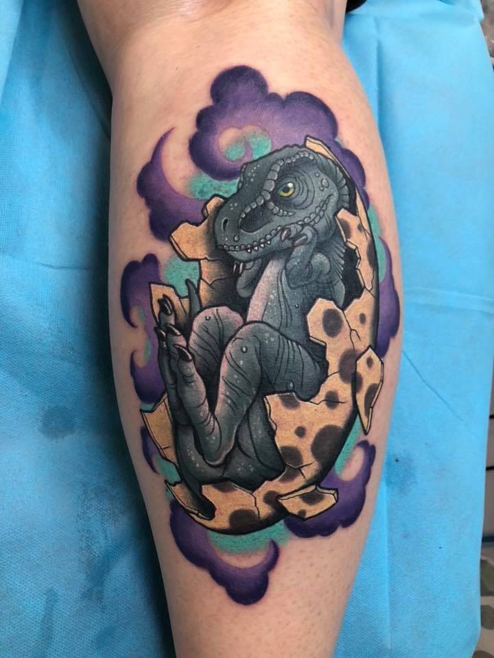Little dinosur in eggshell tattoo