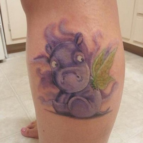 Lovely cartoon violet hippo with green wingstattoo on shin