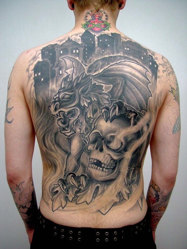 Modern style black ink whole back tattoo of gargoyle combined with human skull in fron of night city