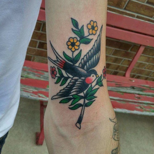 Tatuaje en el brazo,
ave negra y flores preciosas