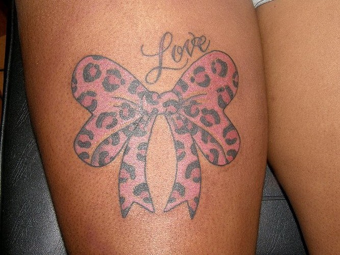 Tattoo von rosa Schleife mit Gepardenmuster und Inschtift &quotLove"  an der Hüfte