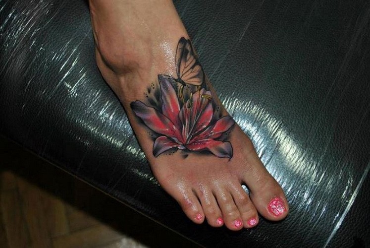 Pretty vivid-colored lily flower and butterfly tattoo on foot