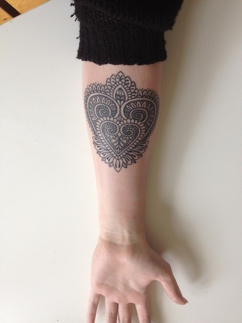 Pretty womens tribal heart-shaped tattoo on forearm