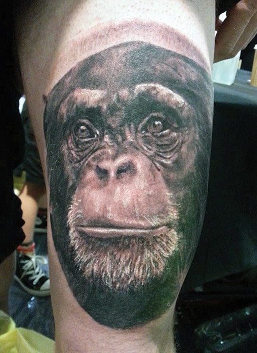 Realistic black-and-white chimpanzee head tattoo on thigh