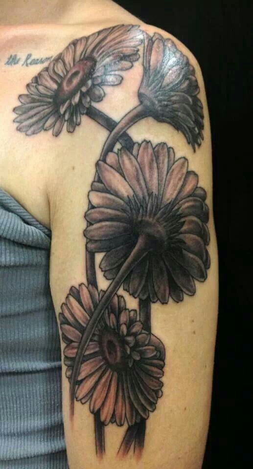 Realistic black-and-white daisy flowers tattoo on upper arm