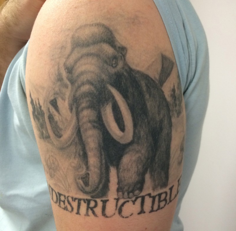 Realistic black-and-white mammoth woth quote tattoo on upper arm