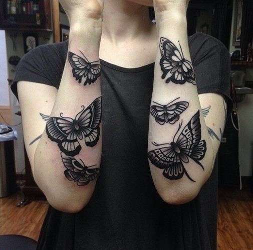 Realistic girly black-ink butterfly tattoo on forearms