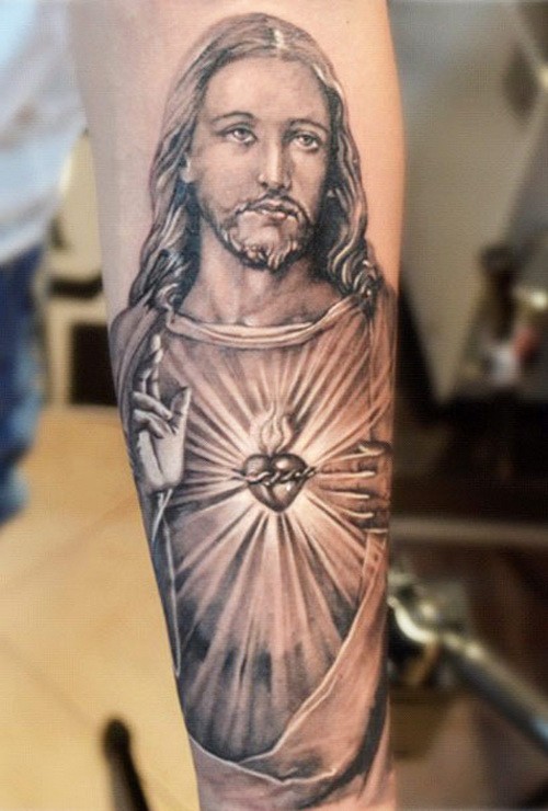 Realistic religious black-and-white Jesus with shining heart tattoo on forearm