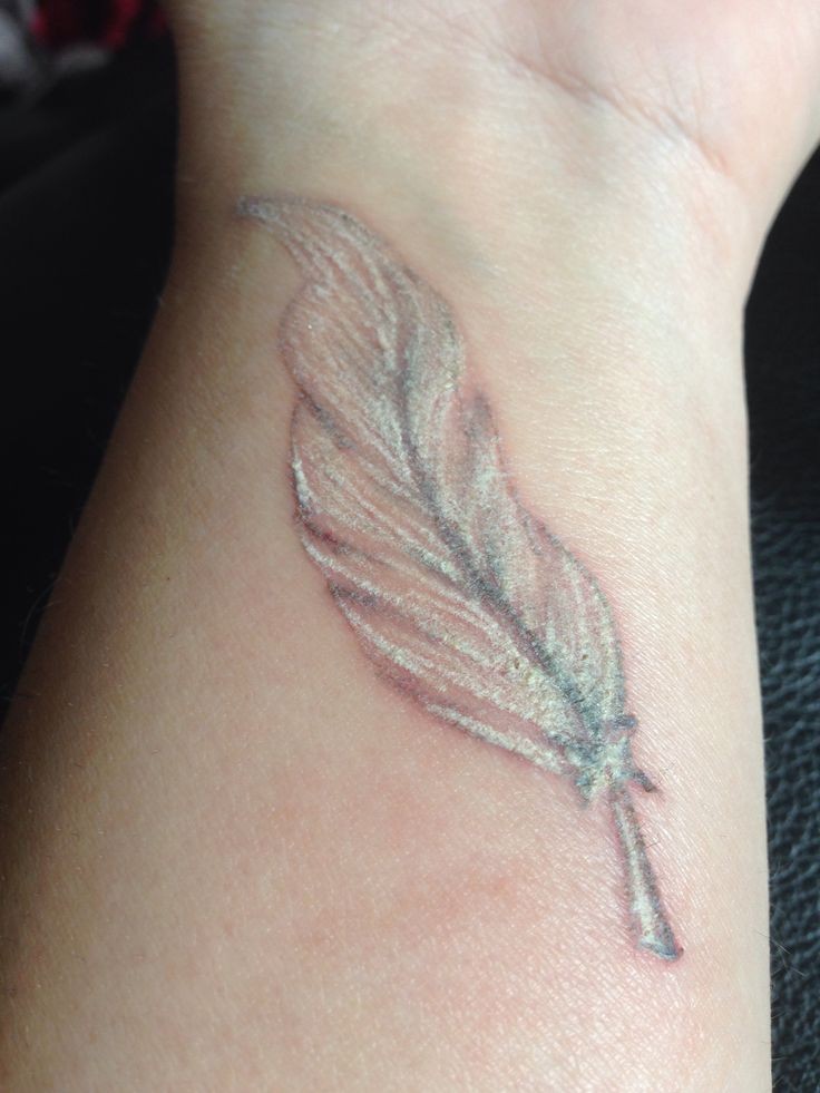Realistic white-ink feather tattoo on wrist