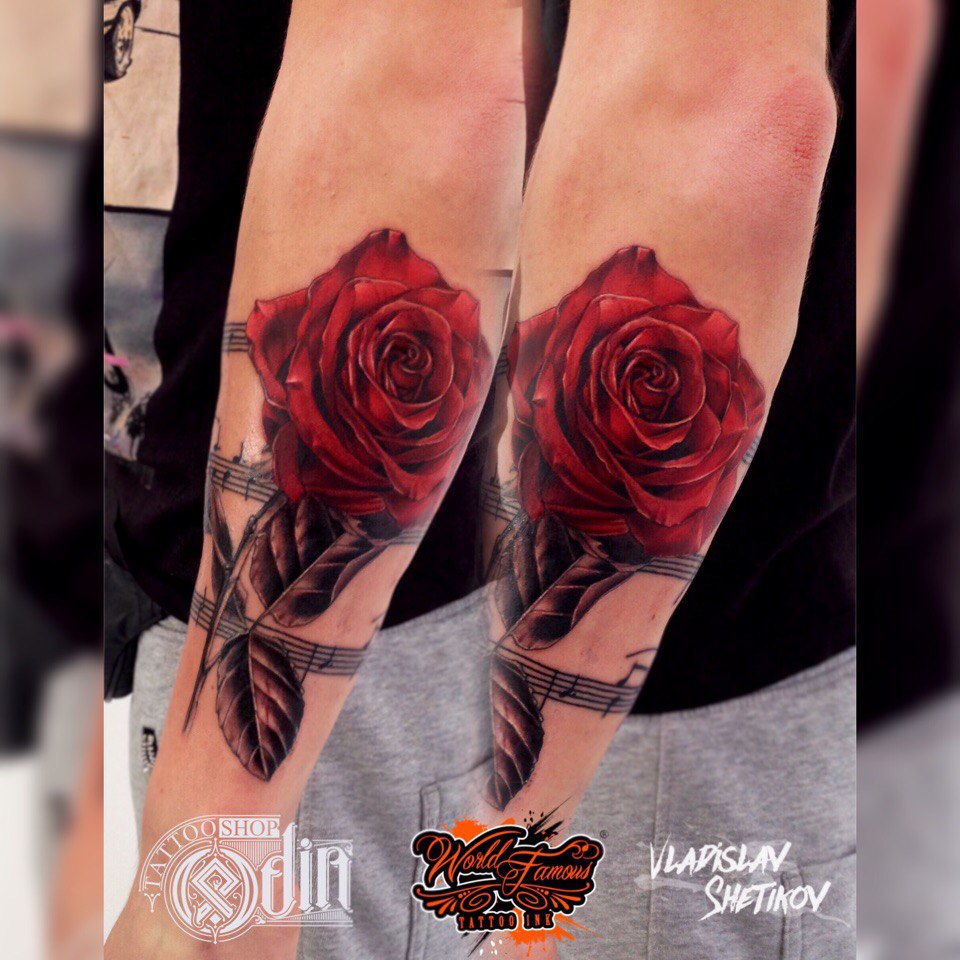 Tatuaje de rosas rojas y notas musicales en el antebrazo