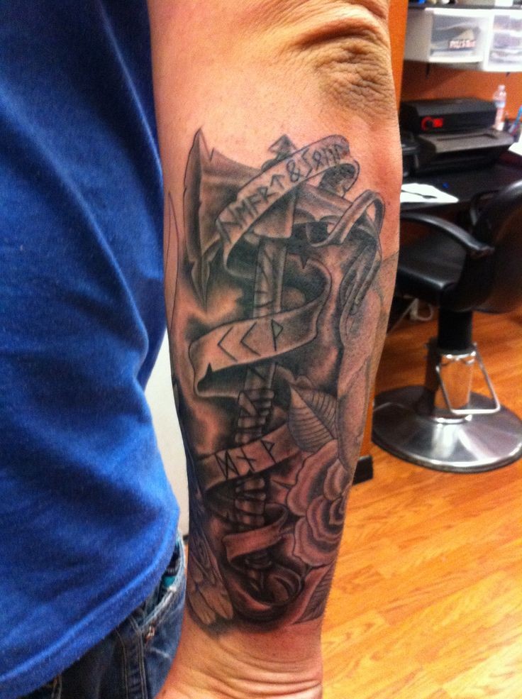 Rough dark axe with lettered ribbon tattoo on outer forearm