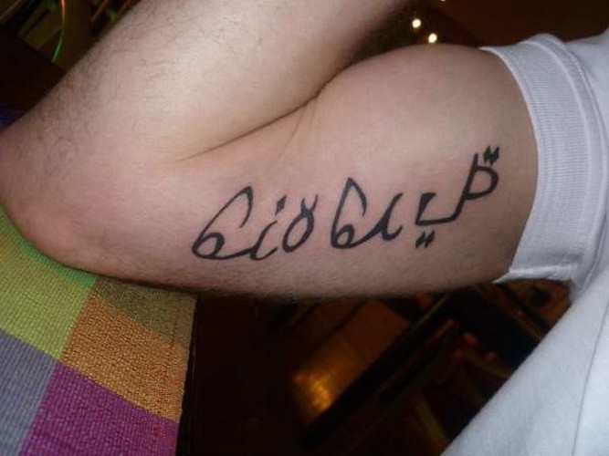 Simple black-lettered arabic quote tattoo for men on arem