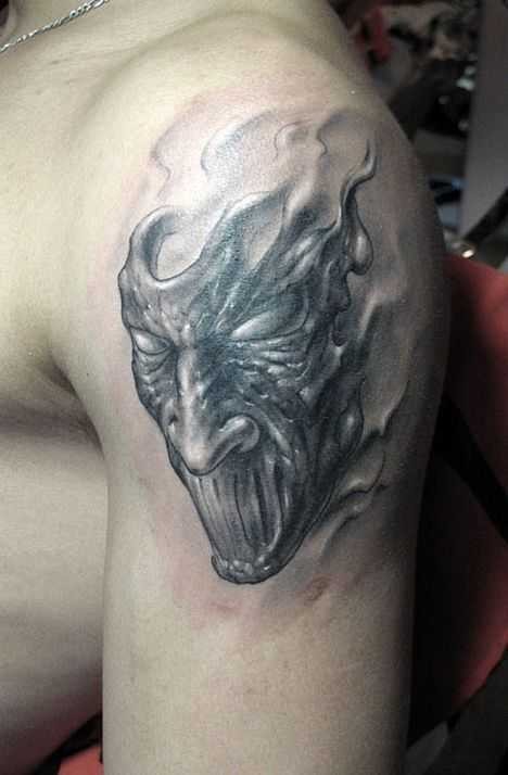 Simple black ink upper arm tattoo of monster mask
