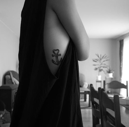 Simple tiny black-and-white anchor with heart on top tattoo on rib-side