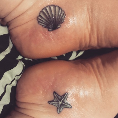 Kleine schwarzweiße Seestern und Shell Tattoo an Füßen