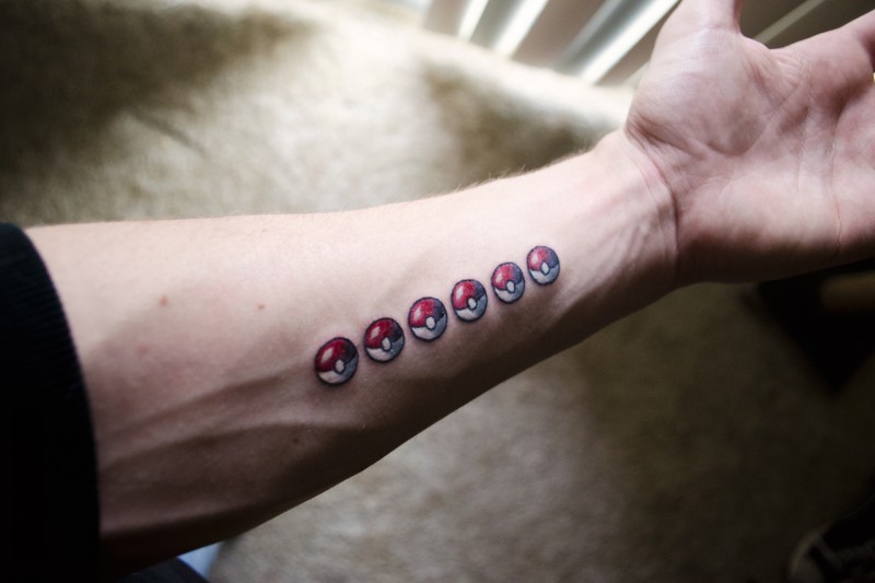 Small funny colorful pocemon balls tattoo on forearm