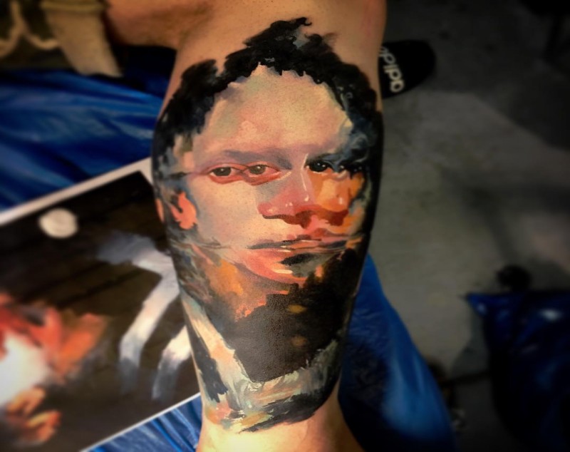 Surrealismo estilo bíceps colorido tatuagem de rosto humano