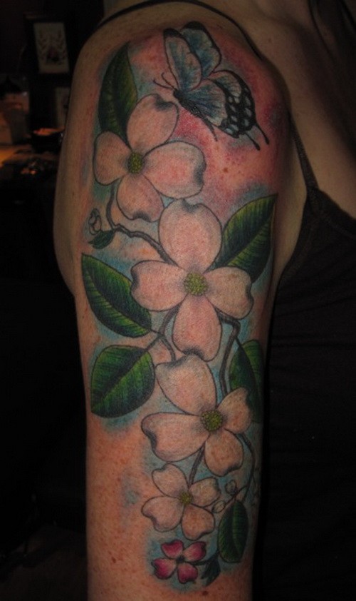 Tender colorful dogwood flowers and butterfly tattoo on upper arm