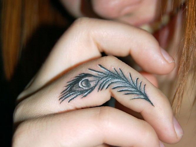 Tiny peacock feather tattoo on finger