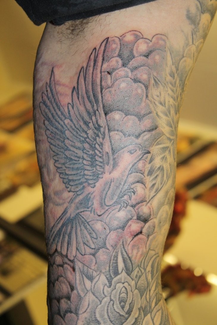 Traditional black-and-white dove with rose tattoo on upper arm