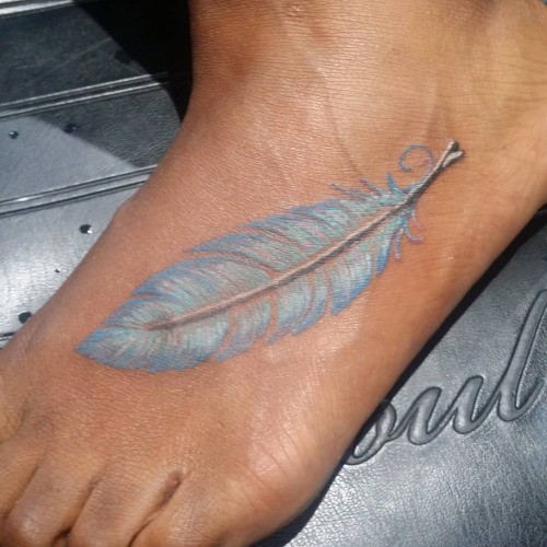 Traditional white feather tattoo on foot