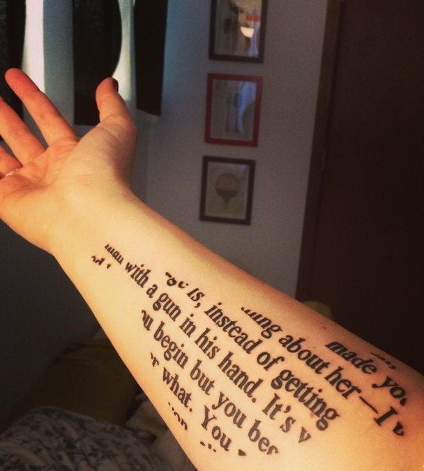 Unusual bird-shaped printed quote tattoo on arm