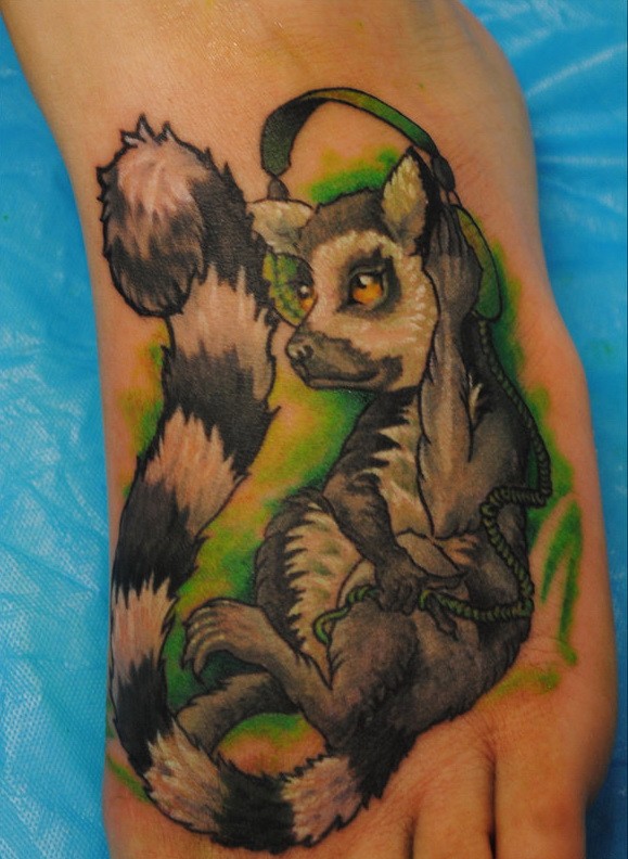 Ungewöhnliches Fuß Tattoo von Lemur mit Kopfhörer auf grünem Hintergrund