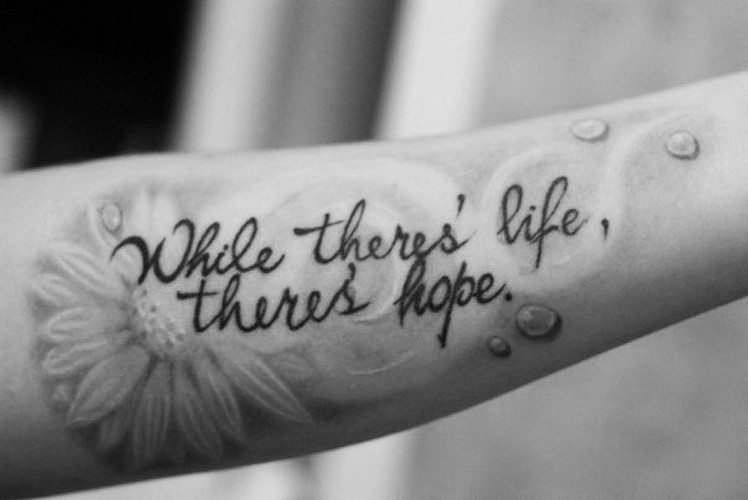 citazione mentre vivi c&quote speranza con fiore camomilla tatuaggio su braccio