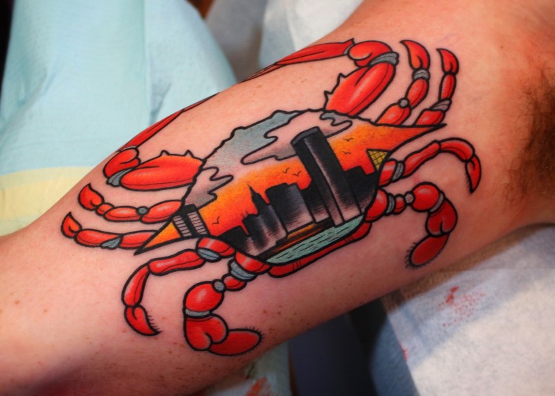 Tatuaje en el brazo, cangrejo surrealista con ciudad