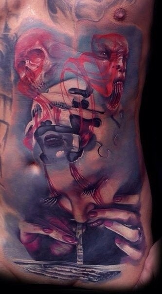 Abstract style colored belly tattoo of mystical faces and skull
