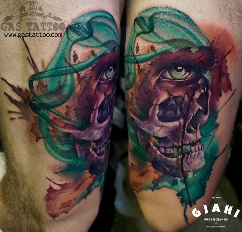 Abstract style colored biceps tattoo of human skull stylized with mystic eye