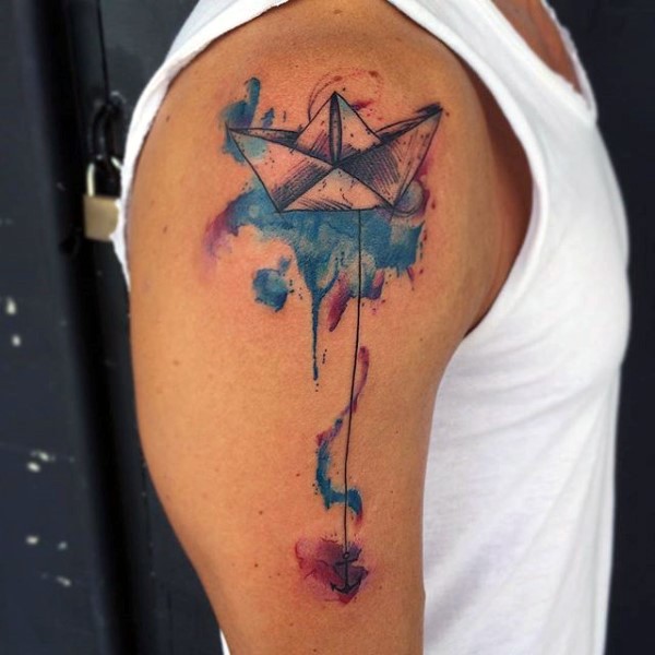 Tatuaje en el brazo, barco de papel con ancla y manchas de acuarelas