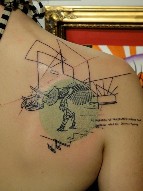 Abstract style colored scapular tattoo of dinosaur skeleton with geometrical figures and lettering