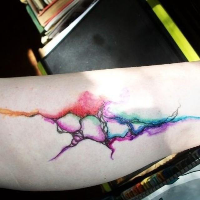 Abstract style little watercolor style painted tattoo on forearm