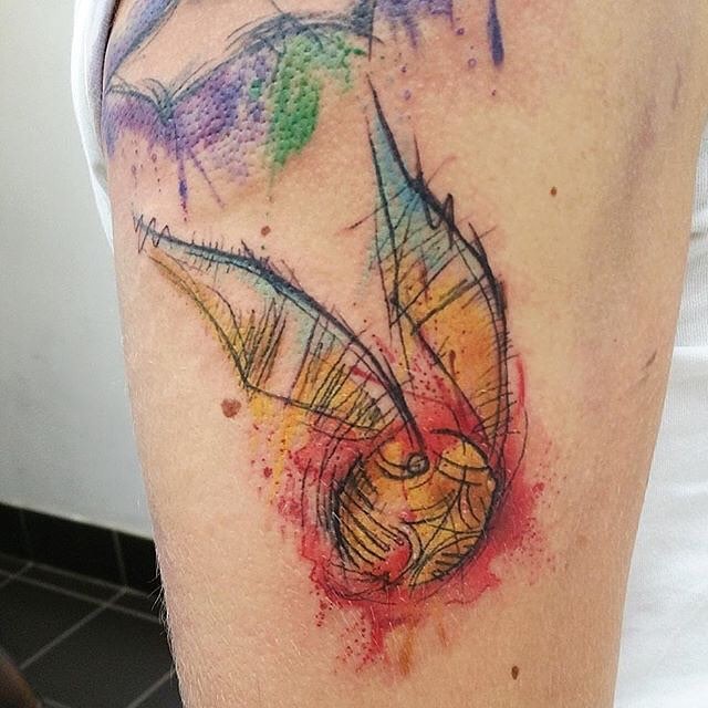 Abstract style watercolor like Harry Potters game ball tattoo on shoulder
