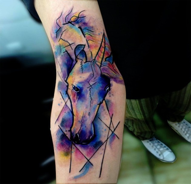 Abstract style watercolor like little forearm tattoo of unicorn head