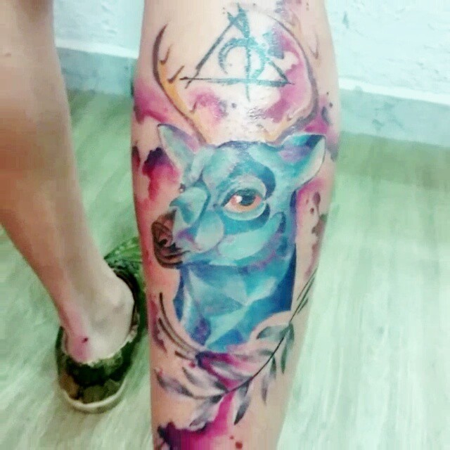 Abstract styli watercolor like little deer tattoo on leg stylized with mystical symbol and leaf