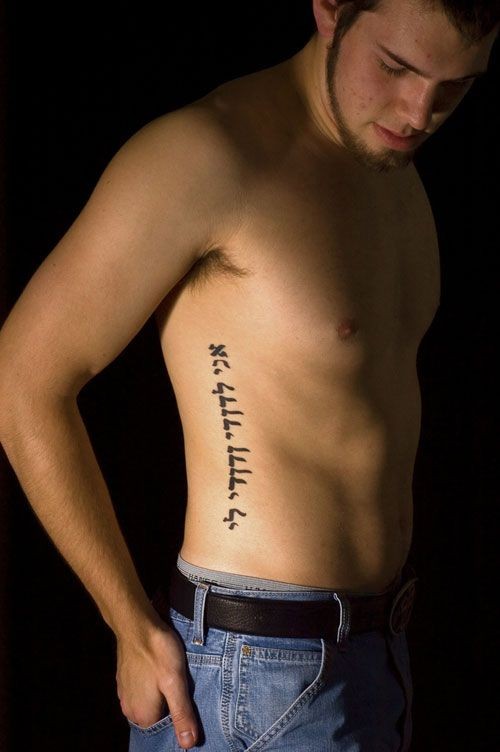 Accurate design dark black ink Arabic lettering tattoo on man&quots side