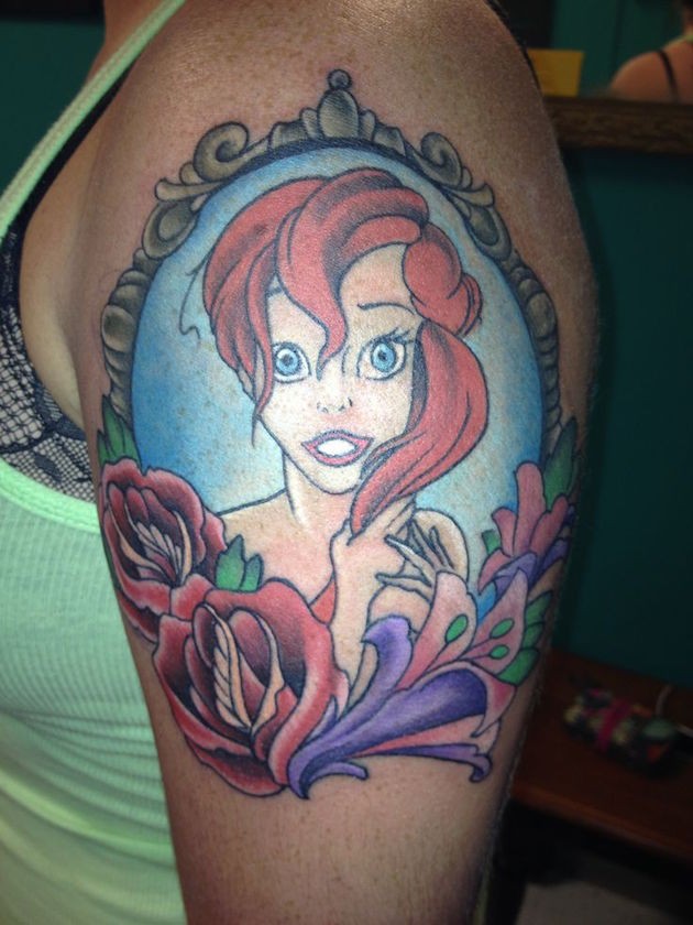 Akkurate und farbige cartoonische Meerjungfrau Porträt Tattoo an der Schulter mit Blumen